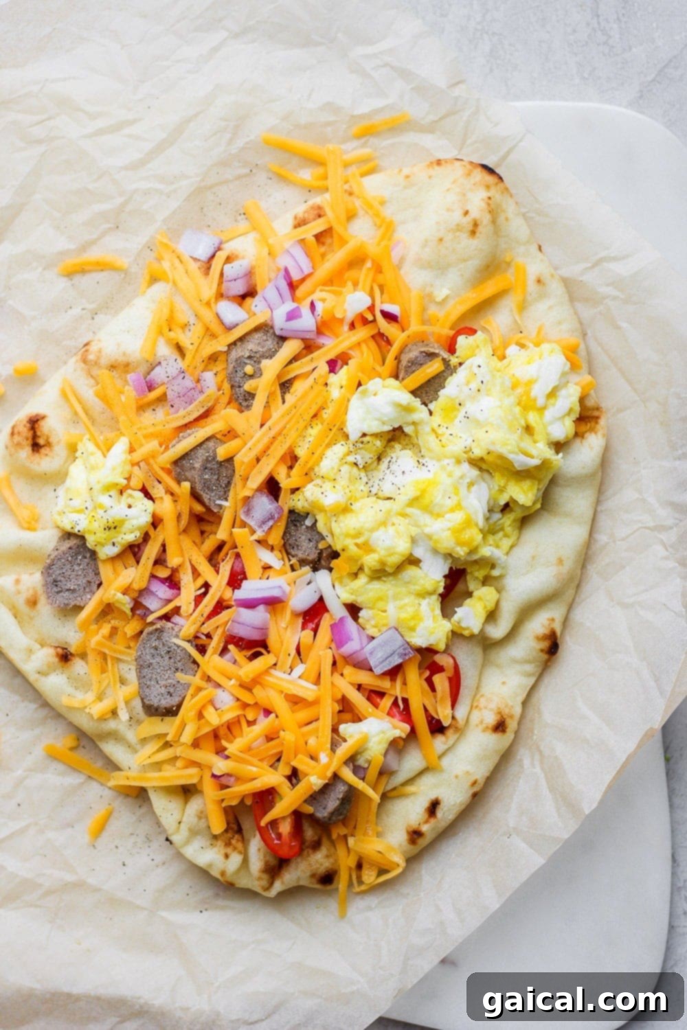 Naan Breakfast Bake 6 Sausage naan pizza loaded with scrambled eggs, cheddar cheese, savory sausage, and red onions.