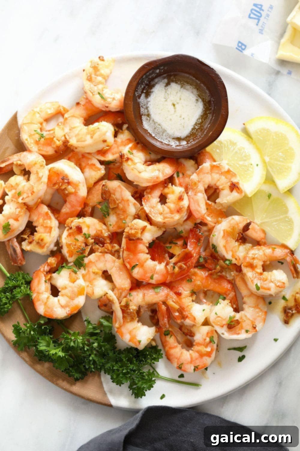 A serving of succulent garlic butter shrimp artfully arranged on a plate, with a small dish of melted butter for dipping.