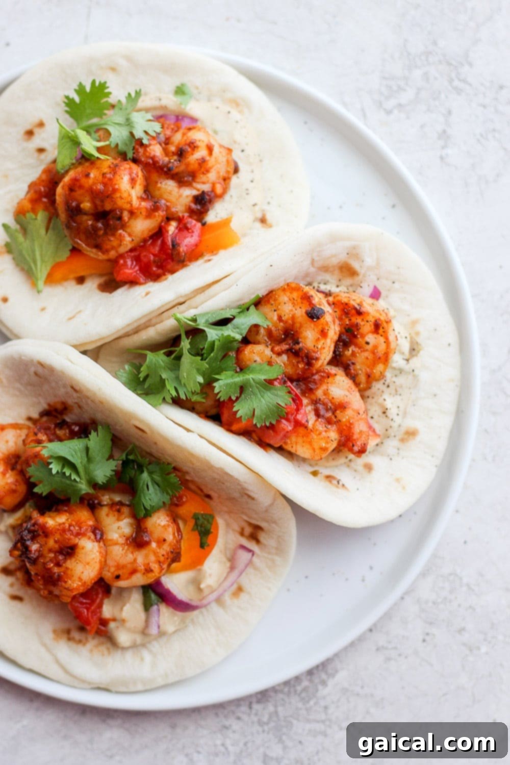 Delicious shrimp tacos topped with fresh cilantro on a white plate, ready to be enjoyed.