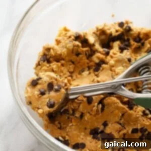 Peanut butter protein balls being mixed in a glass bowl.