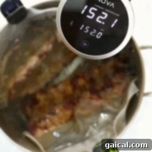 Sous-vide ribs cooking in progress with a digital immersion circulator displaying the water temperature.