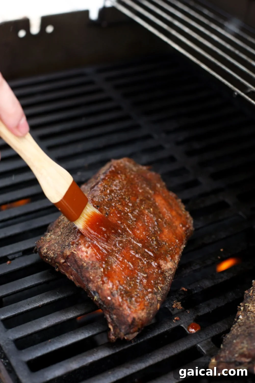 These bbq ribs are rubbed with a smokey dry rub, cooked in a sous vide bath for 24 hours, slathered with BBQ sauce, and then grilled to perfection. Brushing the sous vide ribs with bbq sauce.