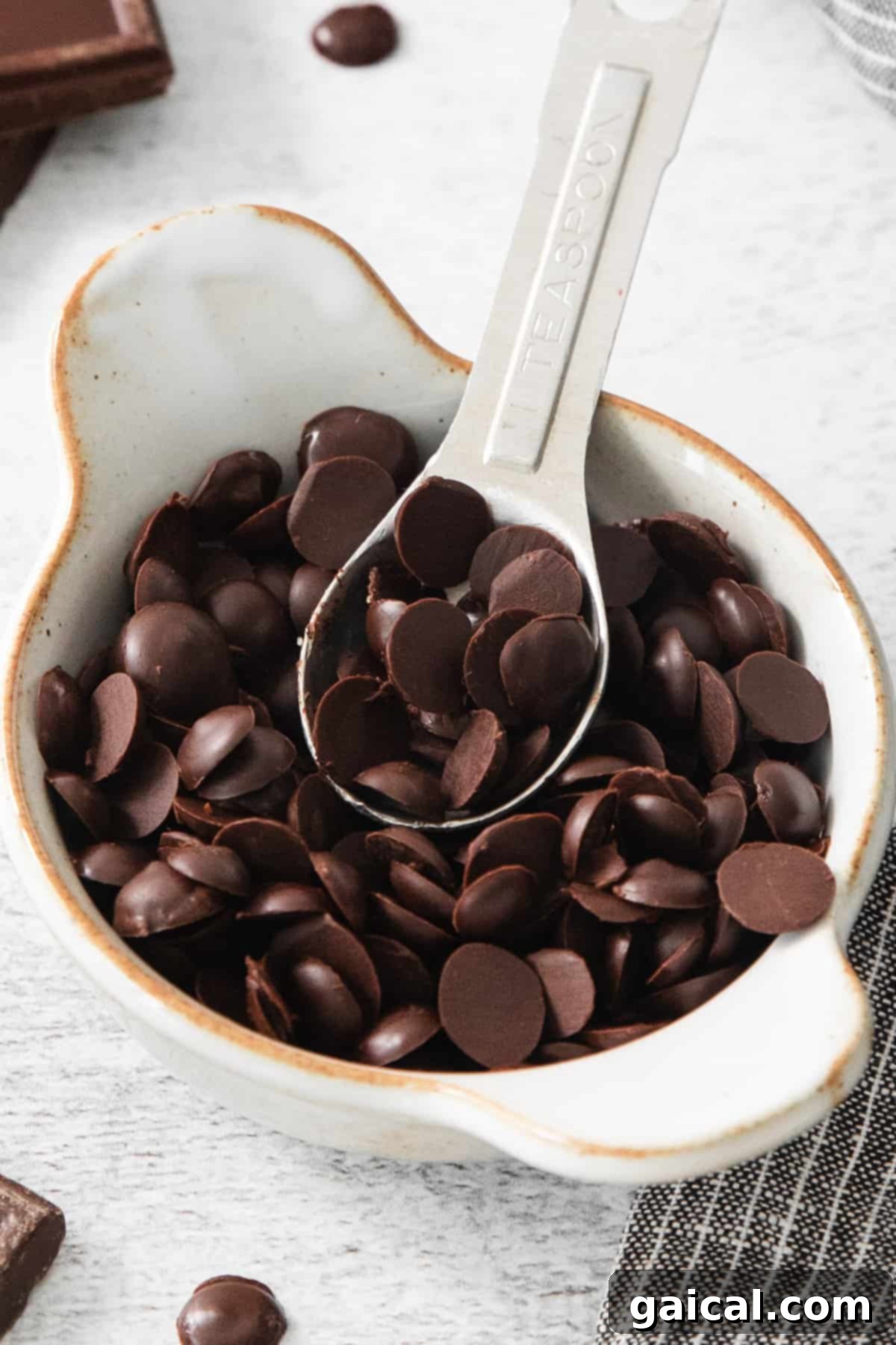 Quick & Easy Homemade Vegan Chocolate Chips 2 Chocolate chips in a white bowl with a spoon.