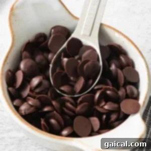 Chocolate chips in a white bowl with a spoon.