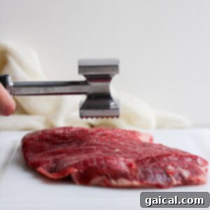 tenderizing flank steak on cutting board.