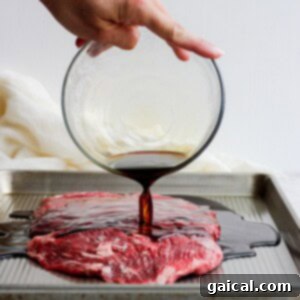 Flank steak marinade being poured over flank steak.