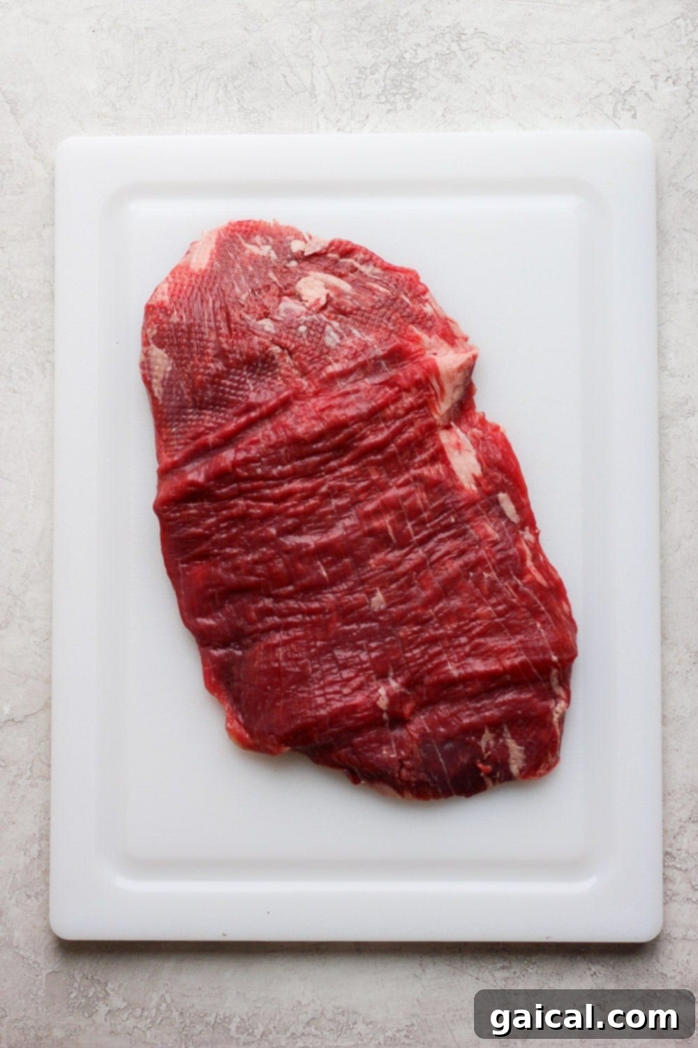 Grill up a flank steak so you can have meal prep flank steak all week long! It's perfect in bowls, for a snack, and everything in between! Pounded flank steak on a cutting board, ready for marinating.