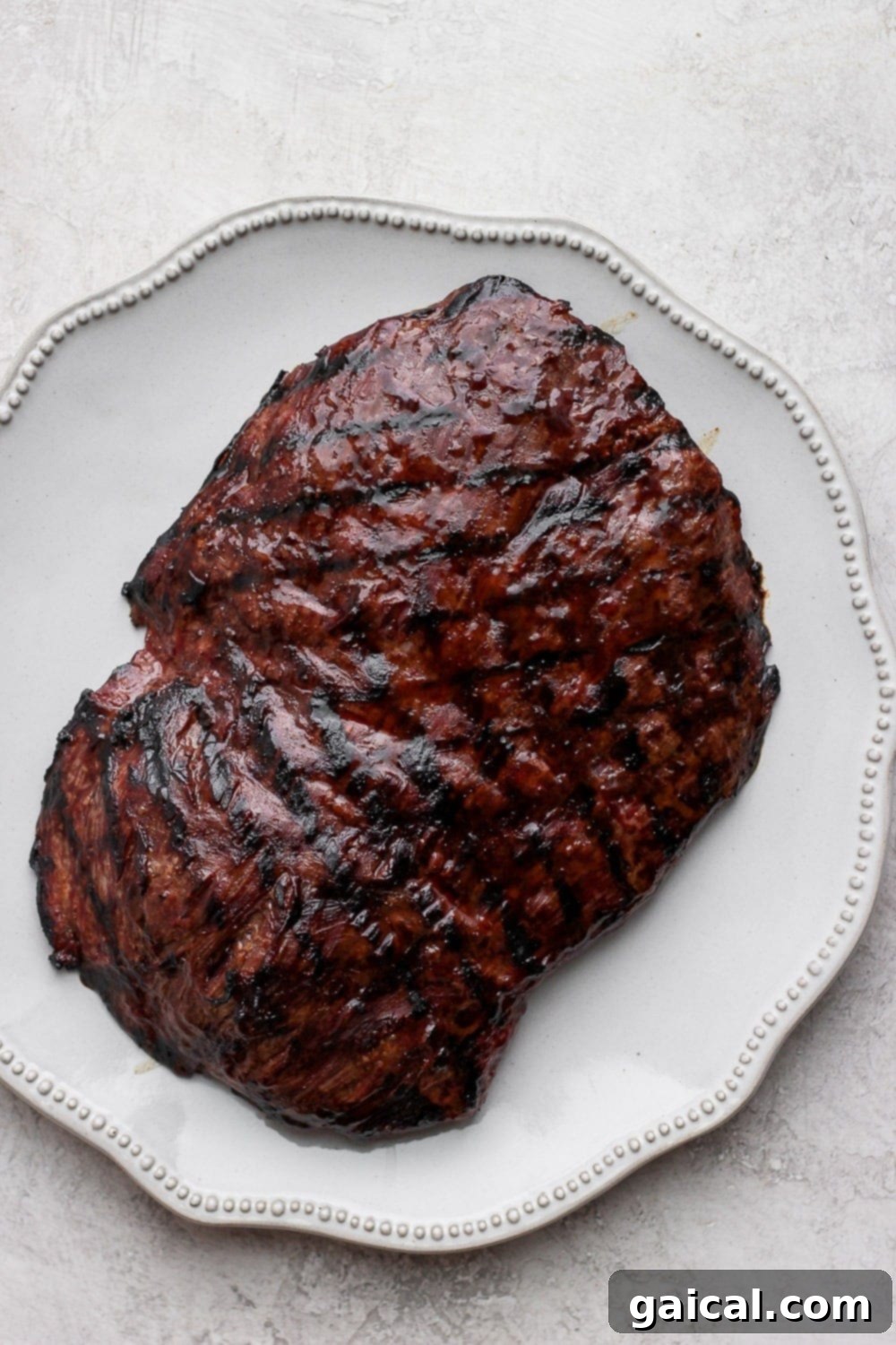 Grilled flank steak is perfect for a weeknight meal! Marinate, grill, and serve! The family will love it! Grilled flank steak sliced into tender strips on a plate.