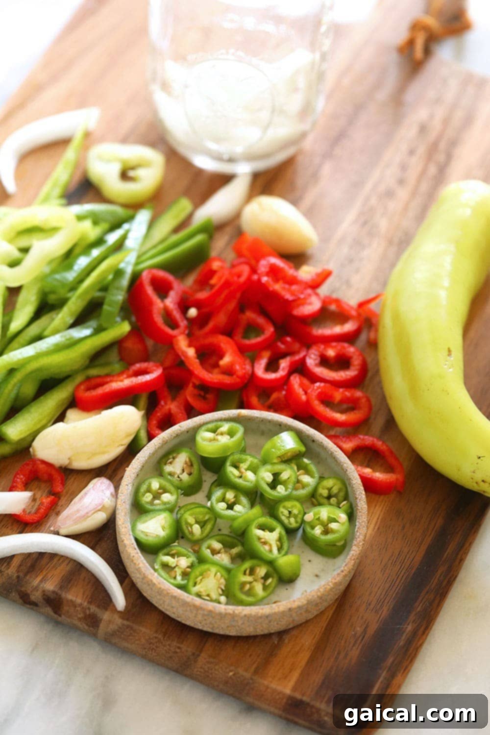 Assortment of sliced peppers and onions ready to be pickled on a cutting board