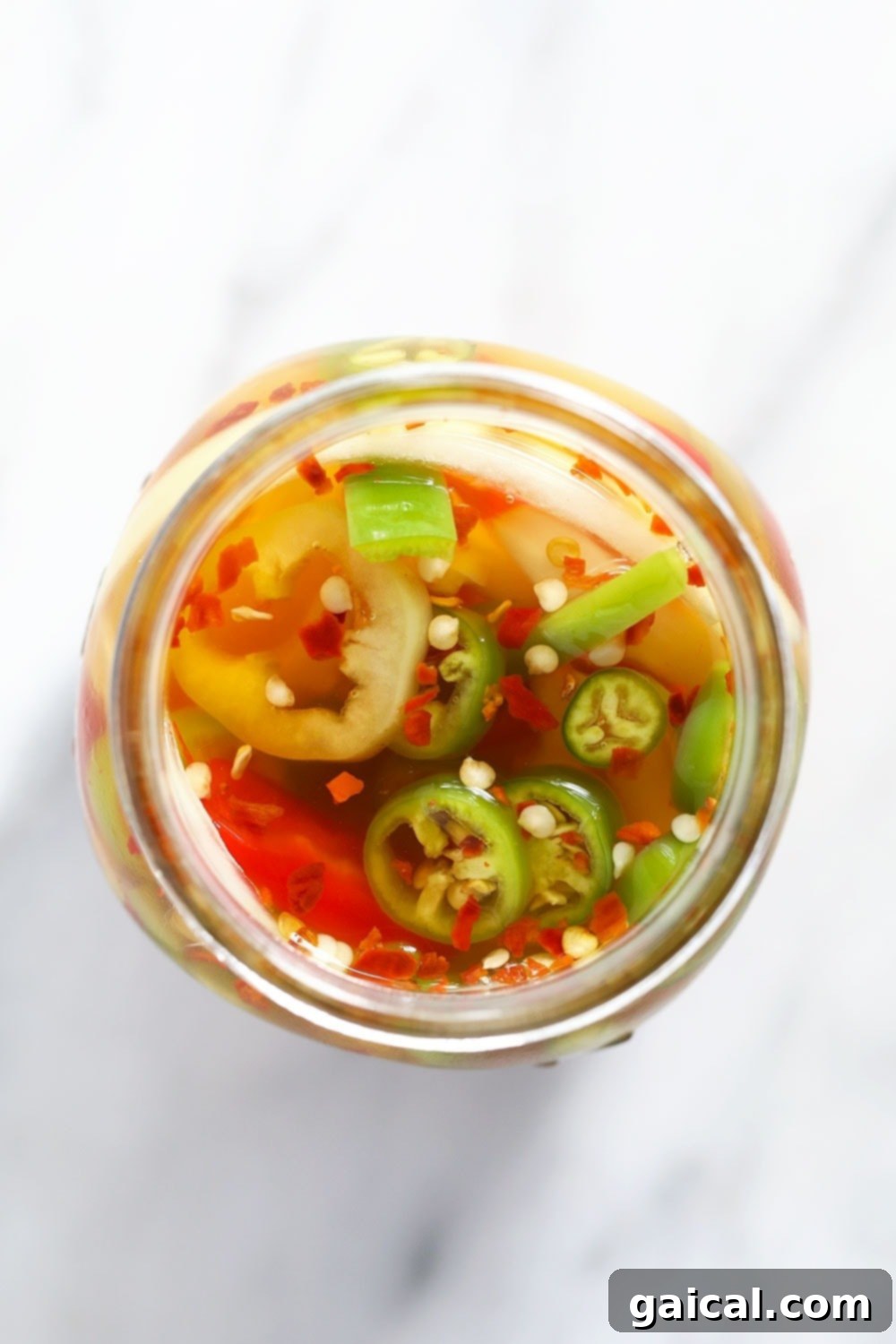 Close-up of quick pickled peppers in a jar, with some air bubbles visible after shaking