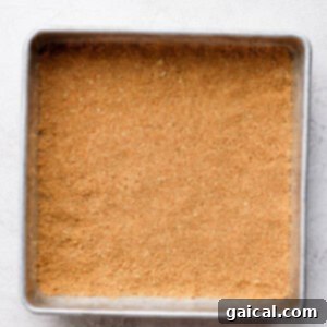 Graham cracker crust pressed into a baking sheet before baking.