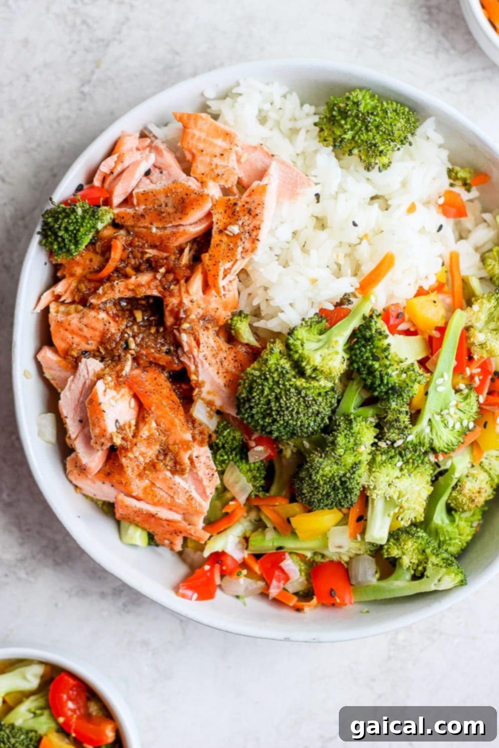 Sheet Pan Asian Salmon Bake 2 Delicious sheet pan salmon stir fry in a bowl with fluffy white rice, ready to be enjoyed.