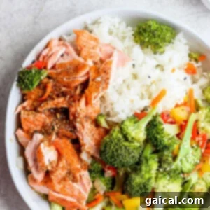 Sheet pan salmon stir fry in a bowl, showing flaky salmon and colorful roasted vegetables drizzled with sauce.