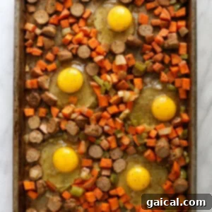 Sweet potato hash with raw eggs cracked into individual wells on the baking sheet, seasoned and ready for the final bake.