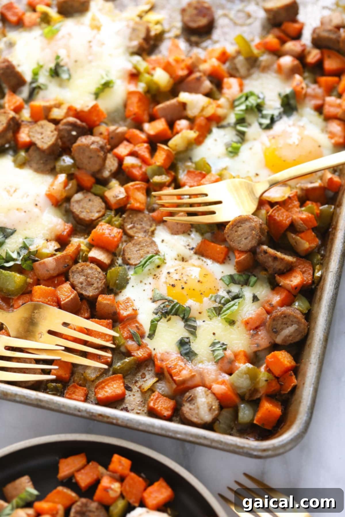 Sweet potato hash on a baking sheet with two forks, inviting you to dig in.