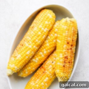 Four ears of perfectly grilled corn on the cob, served in a rustic bowl, garnished and ready to eat.