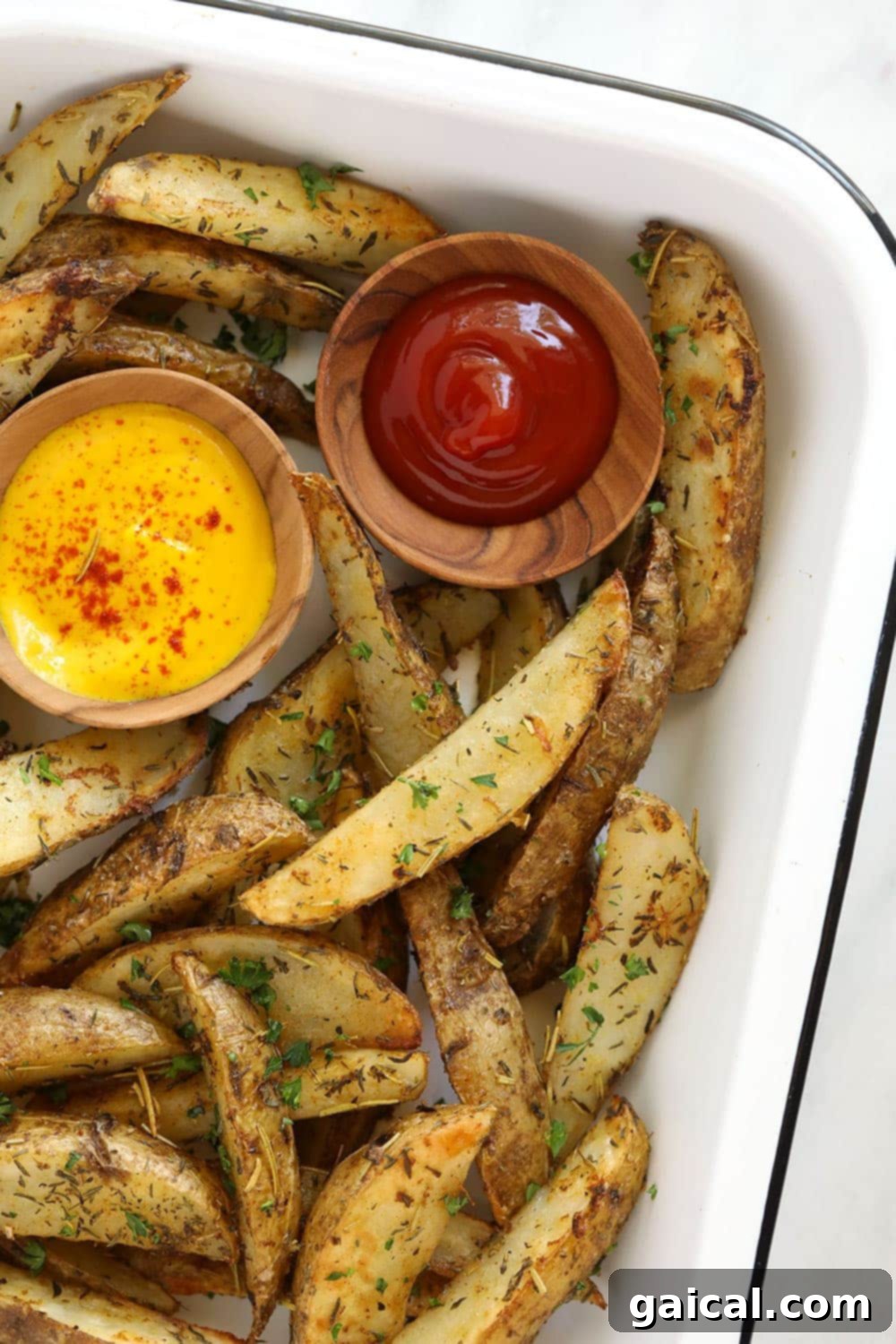 Crispy Roasted Potato Wedges 7 A pan of perfectly baked potato wedges, served with small bowls of ketchup and mustard.