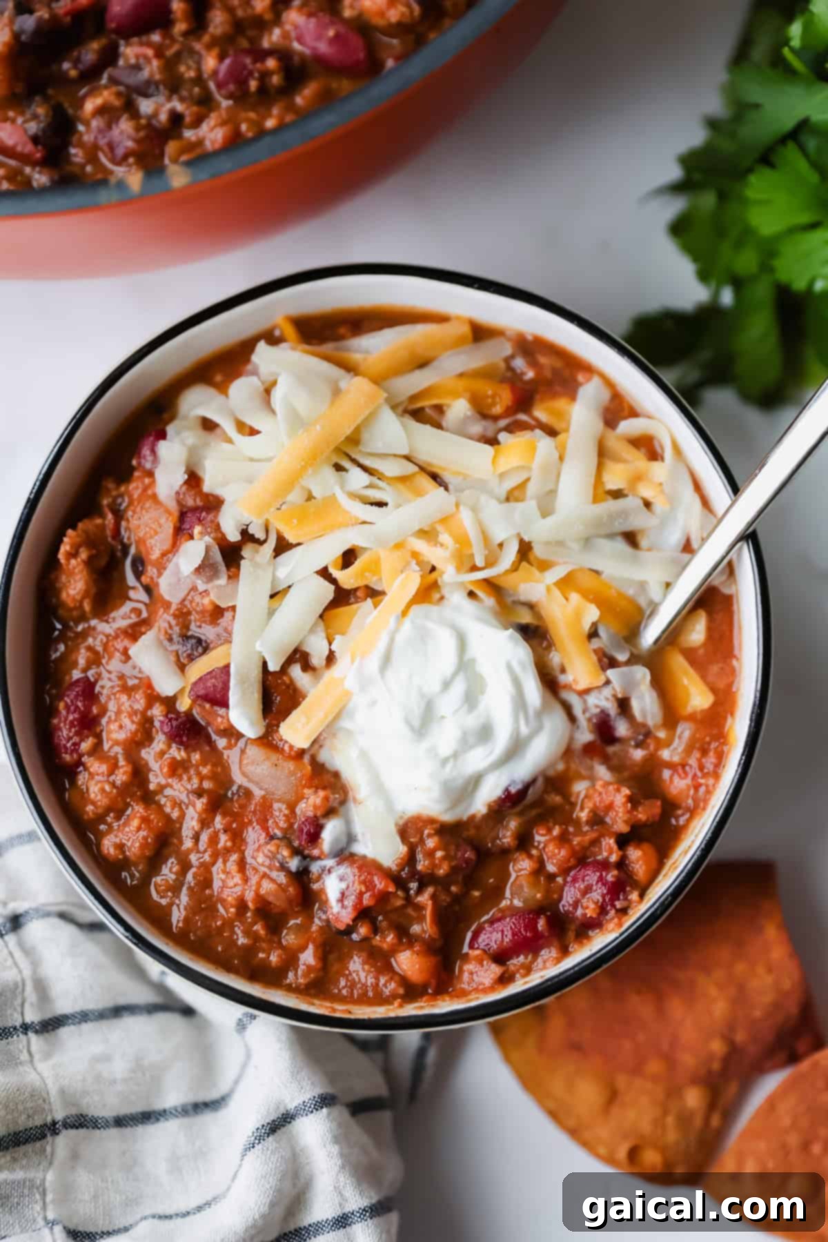 A bowl of Taco Turkey Chili topped with cheese and sour cream.