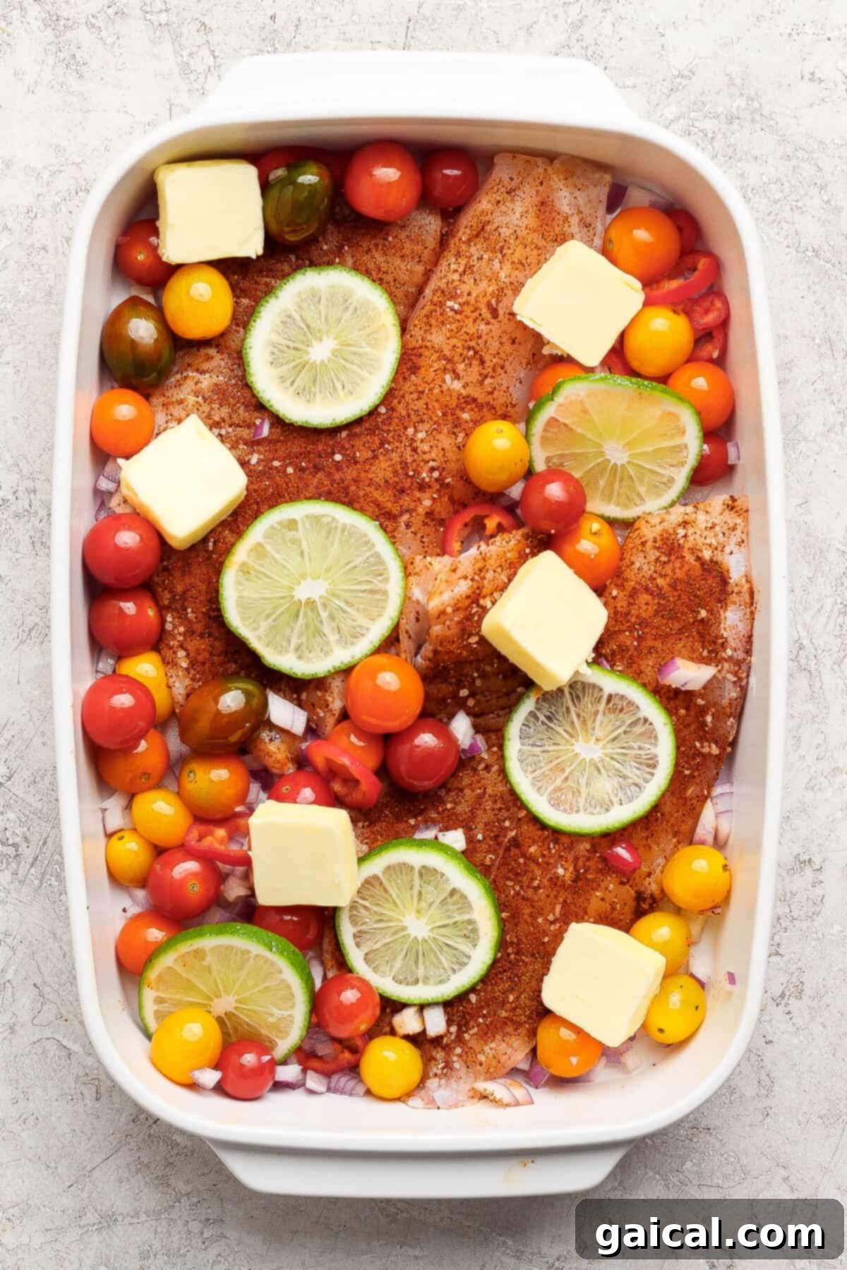 Raw seasoned fish fillets in a baking dish with vegetables.