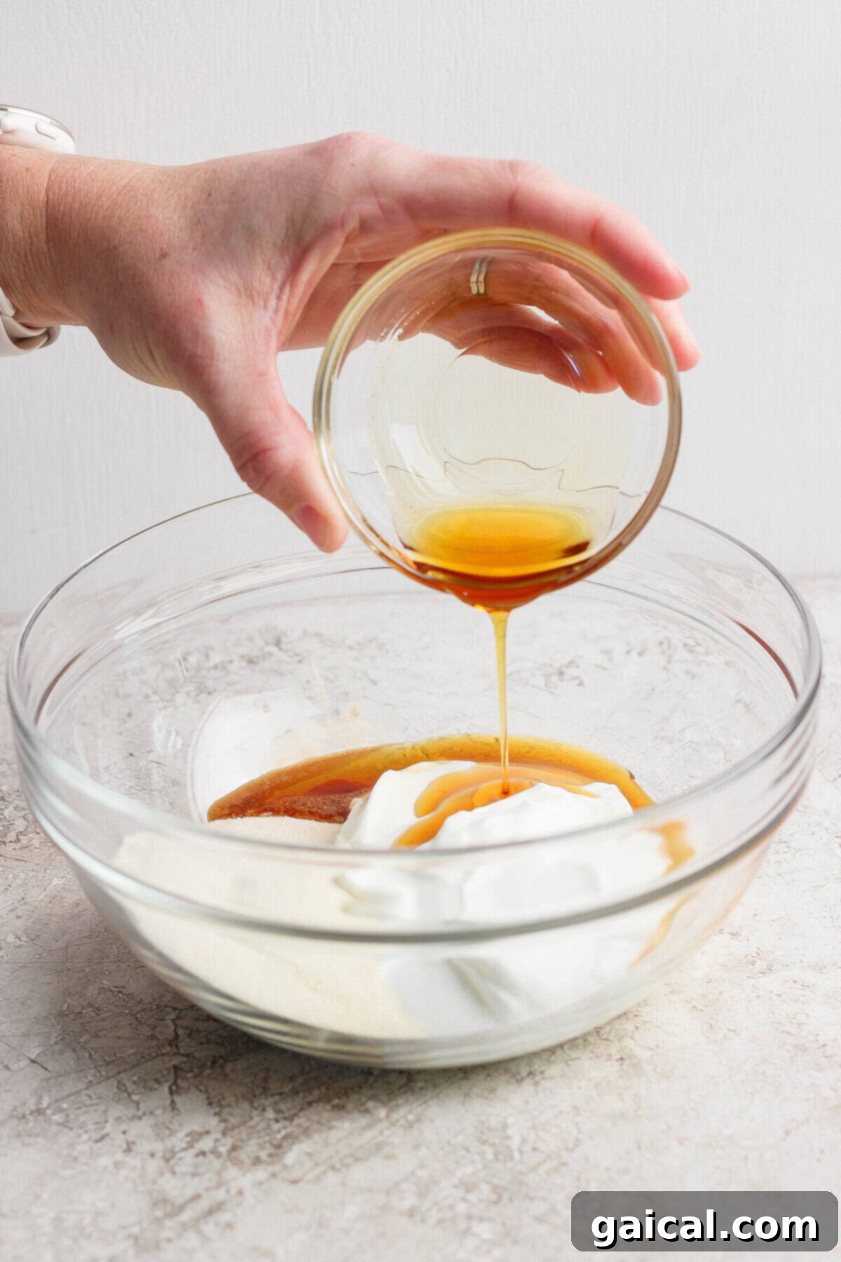 High-Protein Banana Dream 3 Pouring honey into a bowl with yogurt and other ingredients