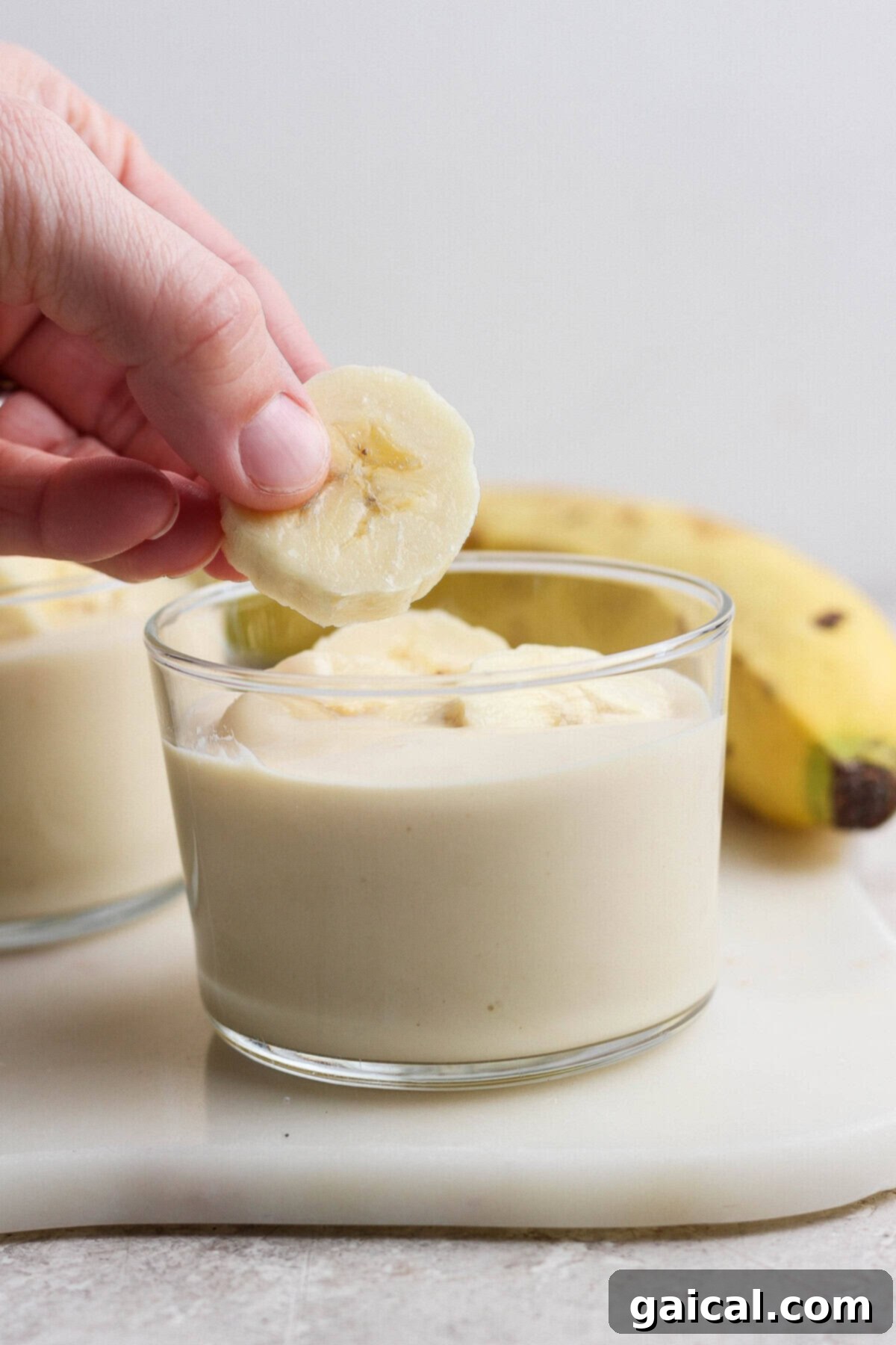 High-Protein Banana Dream 5 Adding banana slices to banana pudding in a glass
