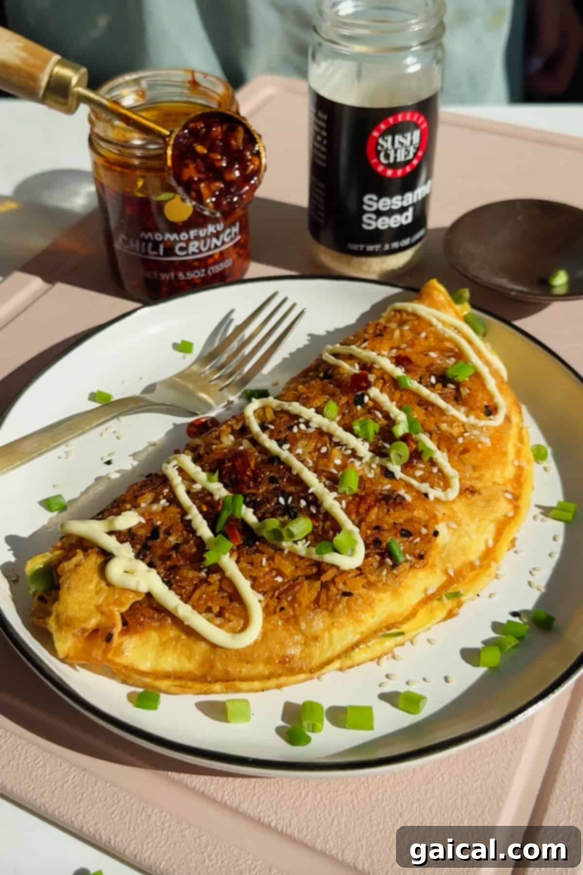 Crispy rice omelette topped with mayonnaise, chili crunch, sesame seeds, and green onions