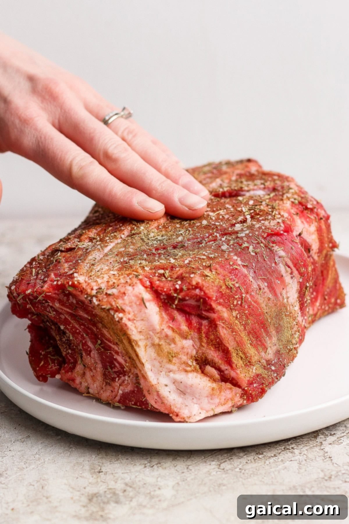 Seasoning a chuck roast with a flavorful spice rub.