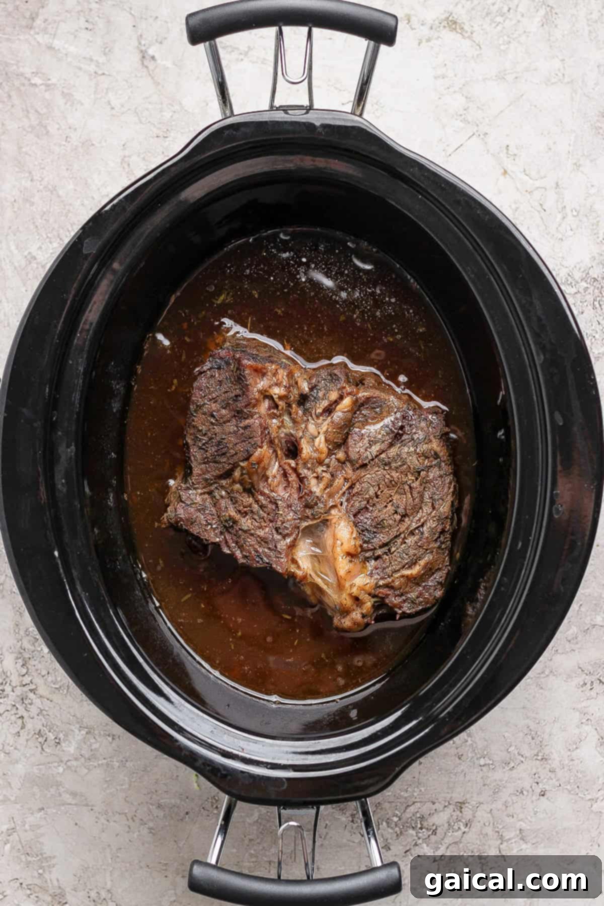 Slow-cooked chuck roast in beef broth, ready to be shredded.