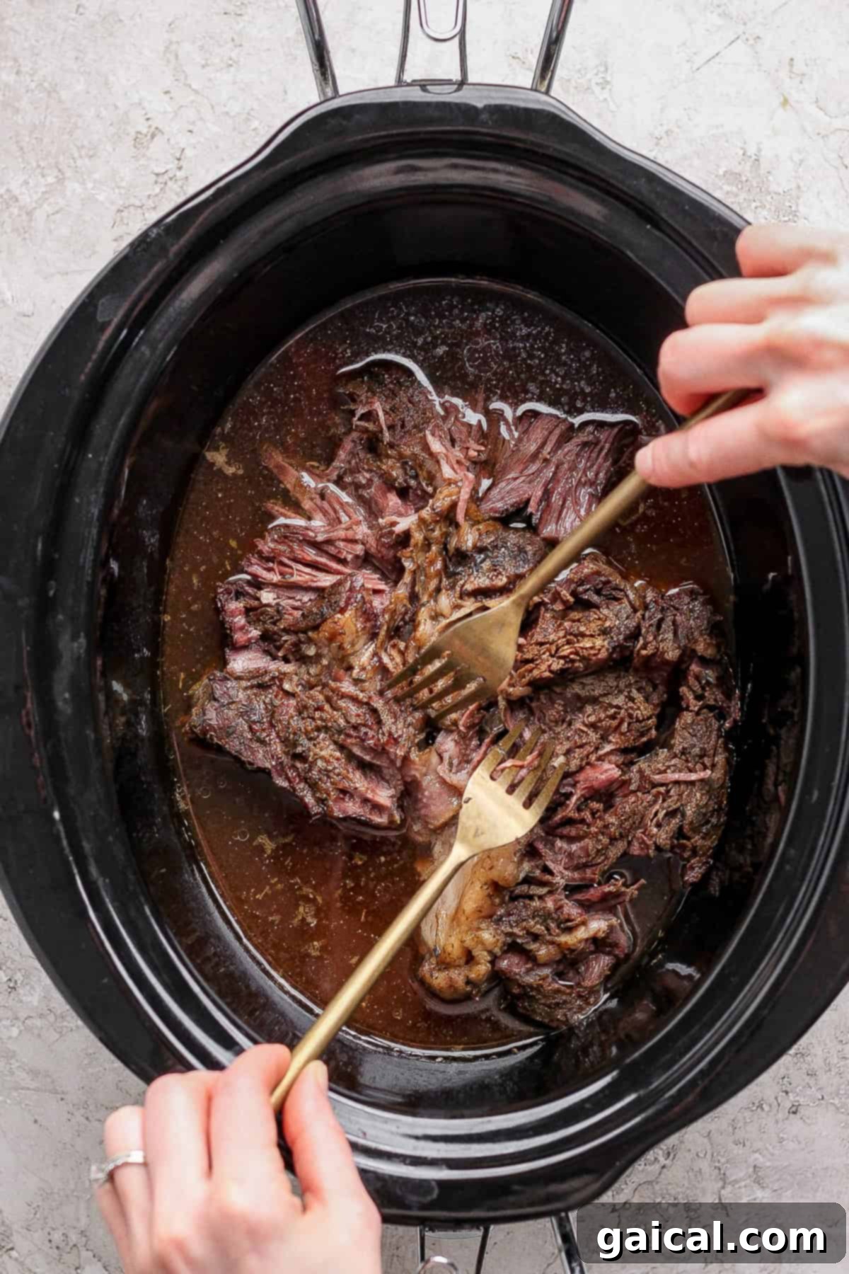 Shredding the slow-cooked beef with two forks.