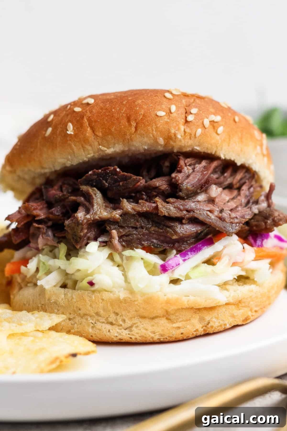 A delicious shredded beef sandwich with coleslaw on a sesame seed bun.
