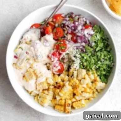 Next Level Street Corn Creations 7 A large bowl of Mexican street corn salad with a creamy dressing and fresh herbs.