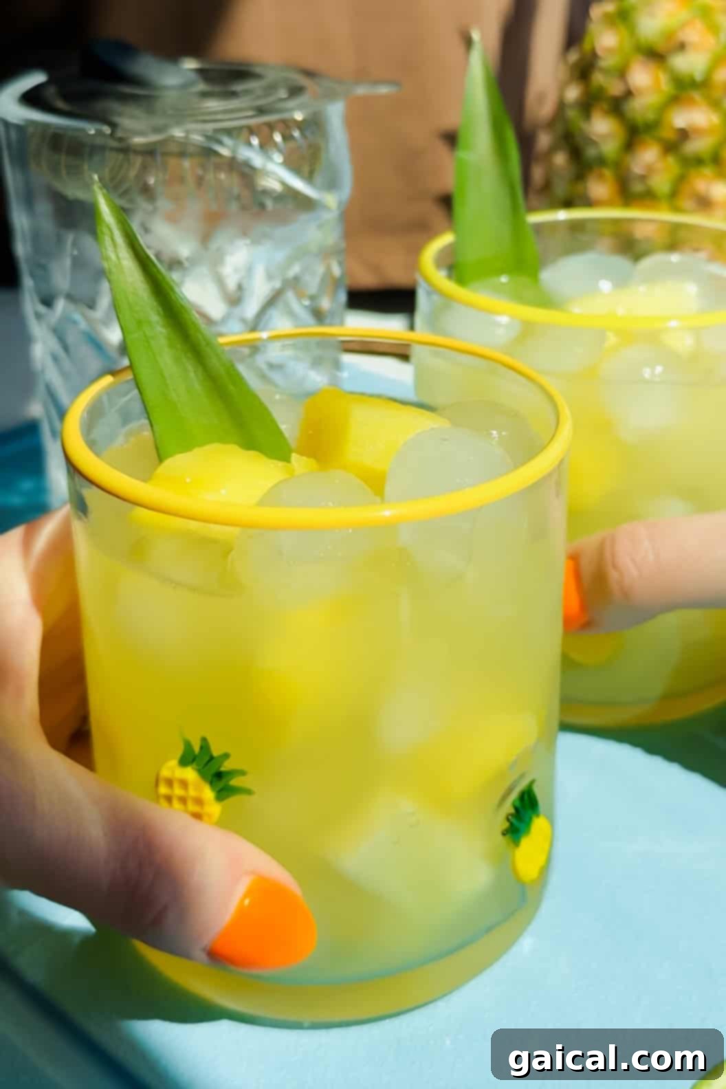 Two vibrant pineapple margaritas being held up in a toast, garnished with fresh pineapple wedges and leaves.