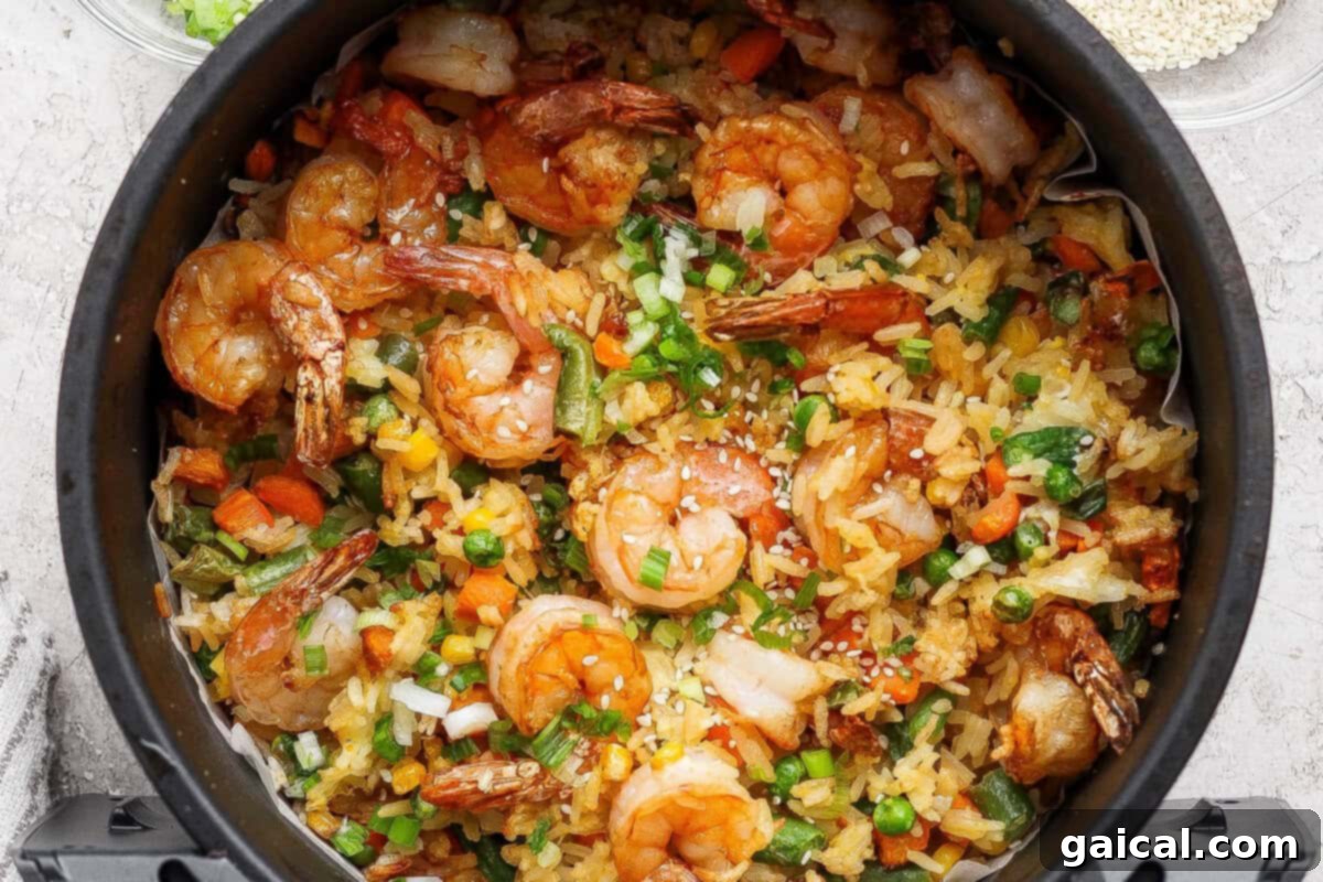 A vibrant bowl of crispy air fryer shrimp fried rice, showcasing golden rice, colorful vegetables, and plump shrimp, garnished with fresh green onions.