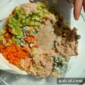 Buffalo Chicken Protein Bars — Crispy Baked Savory Snack 11 Mixing ground chicken, carrots, celery, blue cheese crumbles, and seasonings in a glass bowl for protein bars