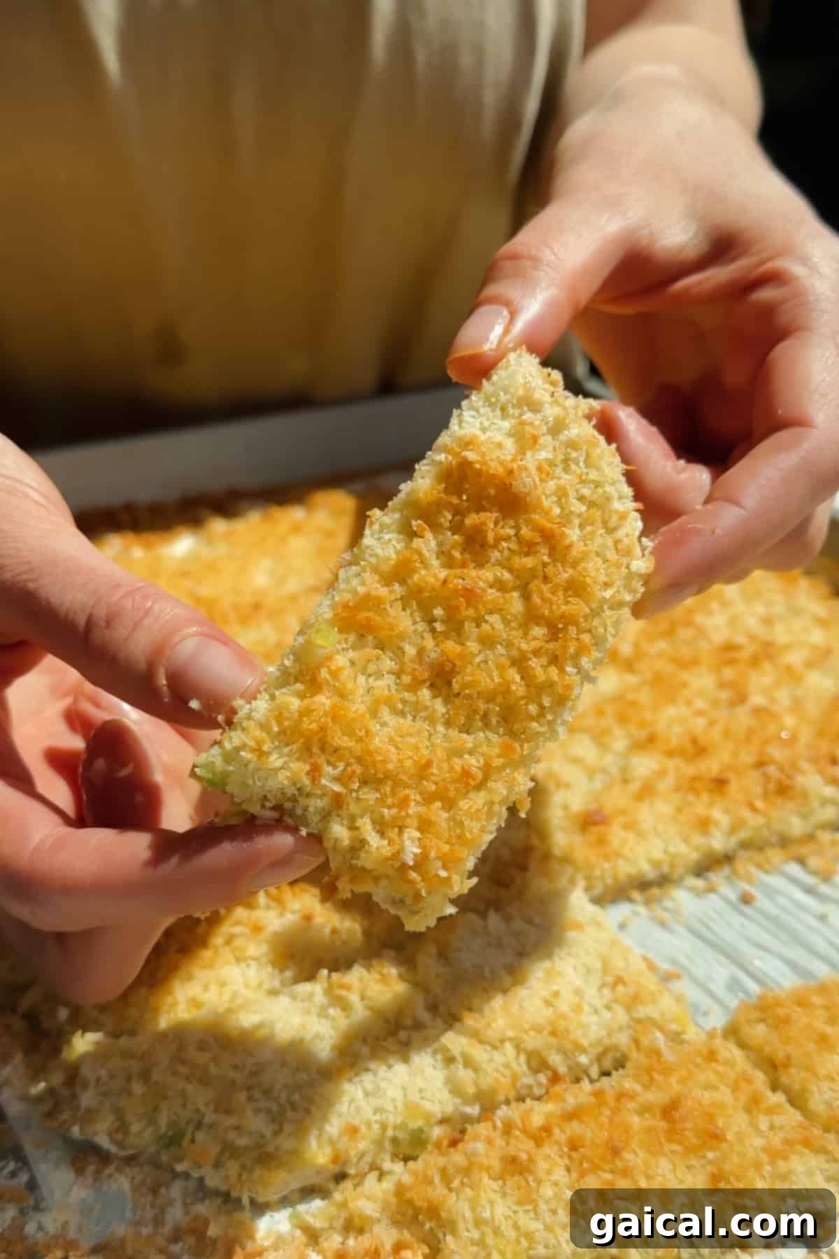 Buffalo Chicken Protein Bars — Crispy Baked Savory Snack 3 Holding a golden crispy chicken protein bar with panko coating above a tray of baked bars