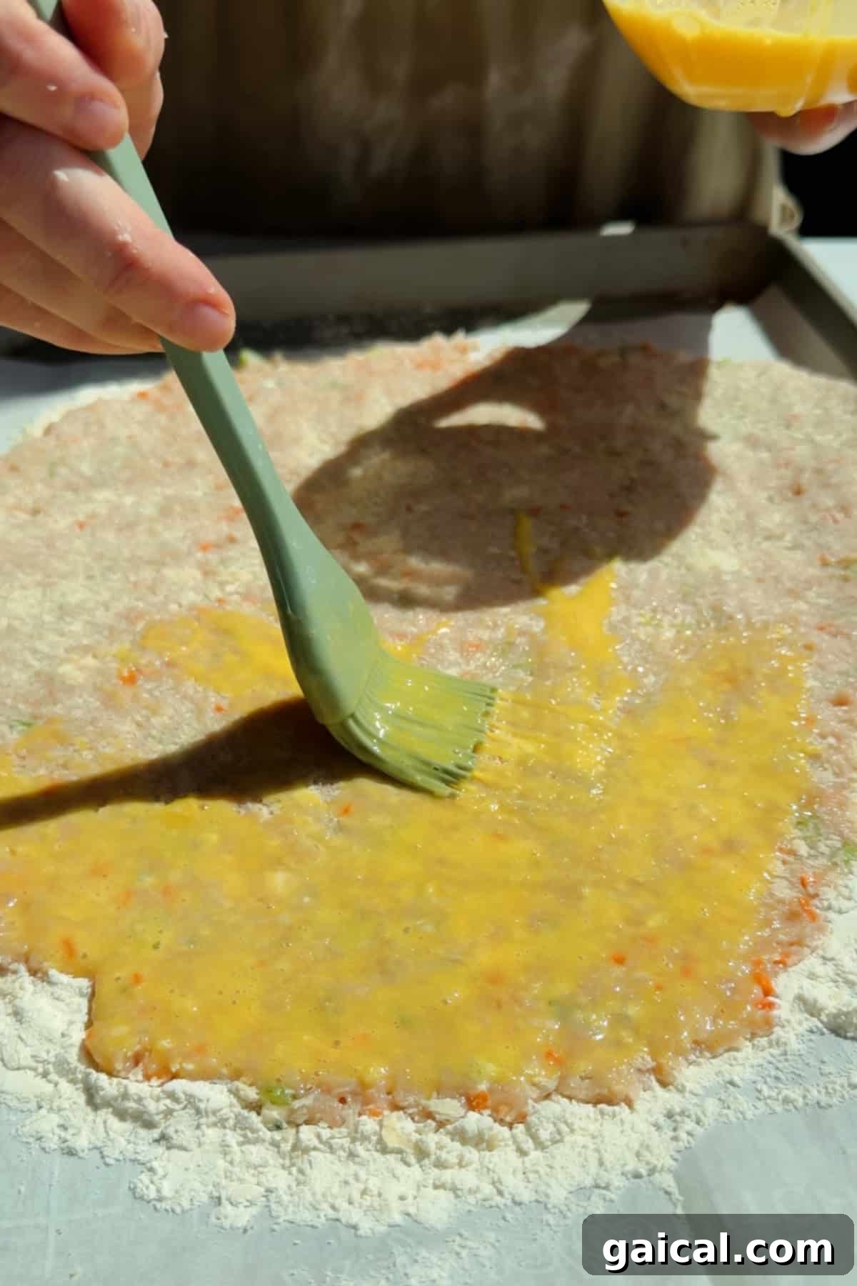 Buffalo Chicken Protein Bars — Crispy Baked Savory Snack 6 Brushing egg wash over chicken protein bar mixture on a floured parchment-lined surface