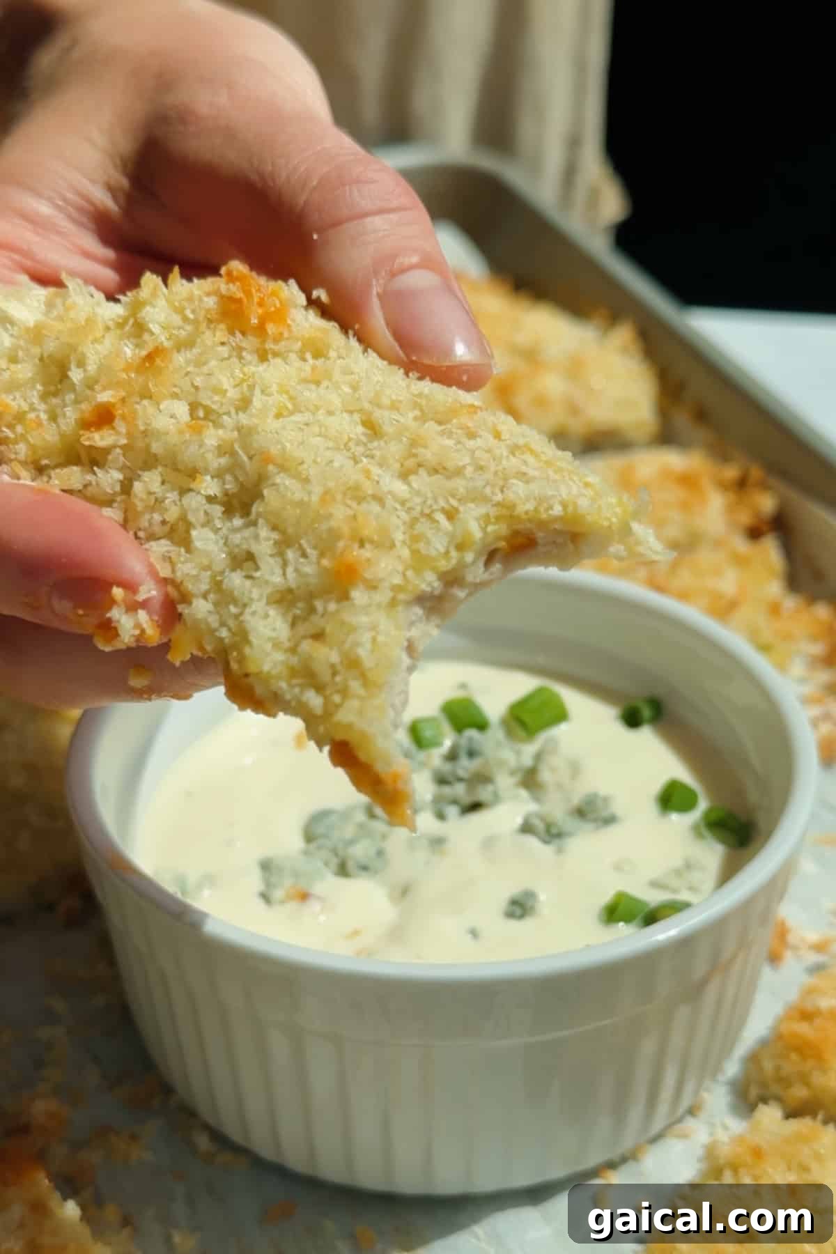 Buffalo Chicken Protein Bars — Crispy Baked Savory Snack 8 Dipping a crispy chicken protein bar into blue cheese dressing topped with crumbled cheese and green onions