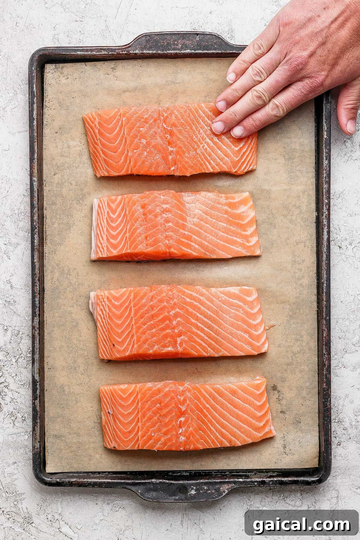 Seasoned salmon fillets arranged on a parchment-lined baking sheet ready for the broiler.