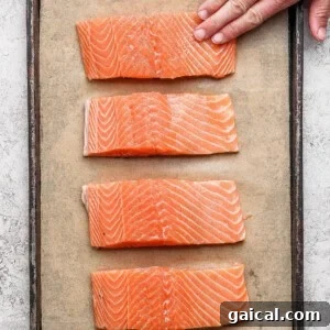 Seasoned salmon fillets arranged on a parchment-lined baking sheet ready to broil.