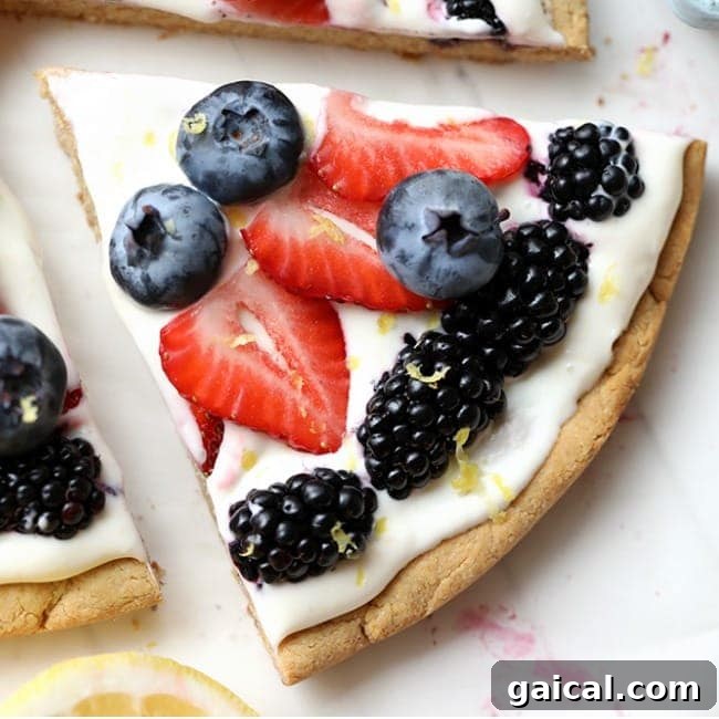 A slice of pizza with berries and lemon on it.
