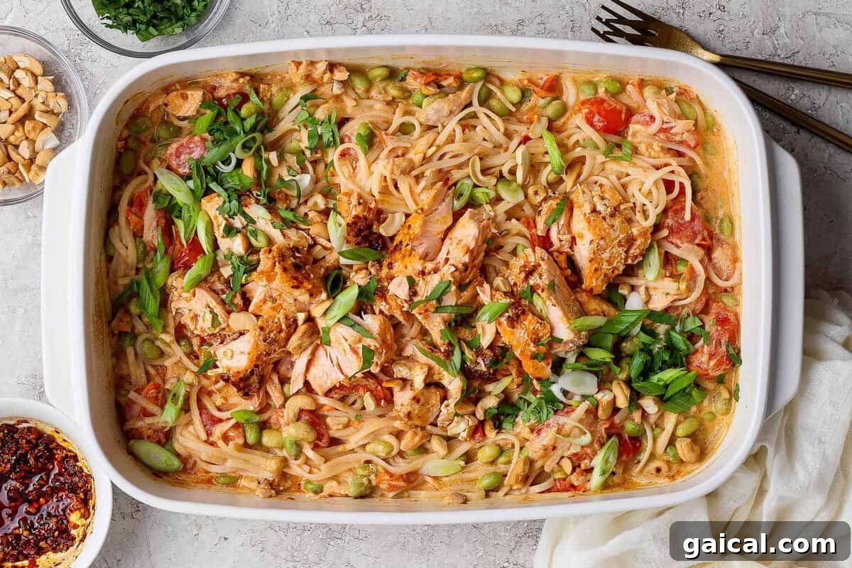 Salmon casserole with rice noodles, baked salmon chunks, cashews, green onions, cilantro, and chili crunch Boursin sauce in a white baking dish