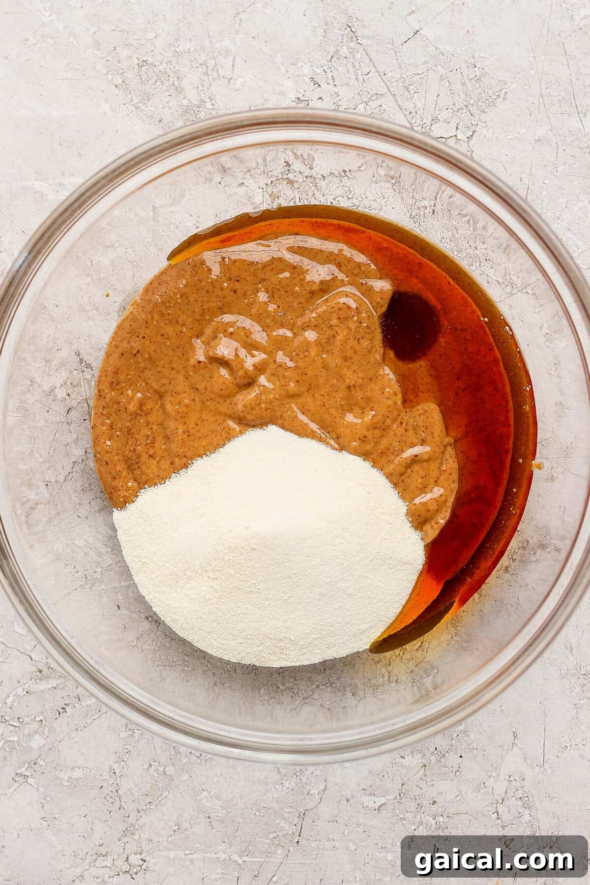 No-Bake Thin Mint Protein Bites 3 mixing almond butter maple syrup and protein powder in a glass bowl for thin mint protein bites