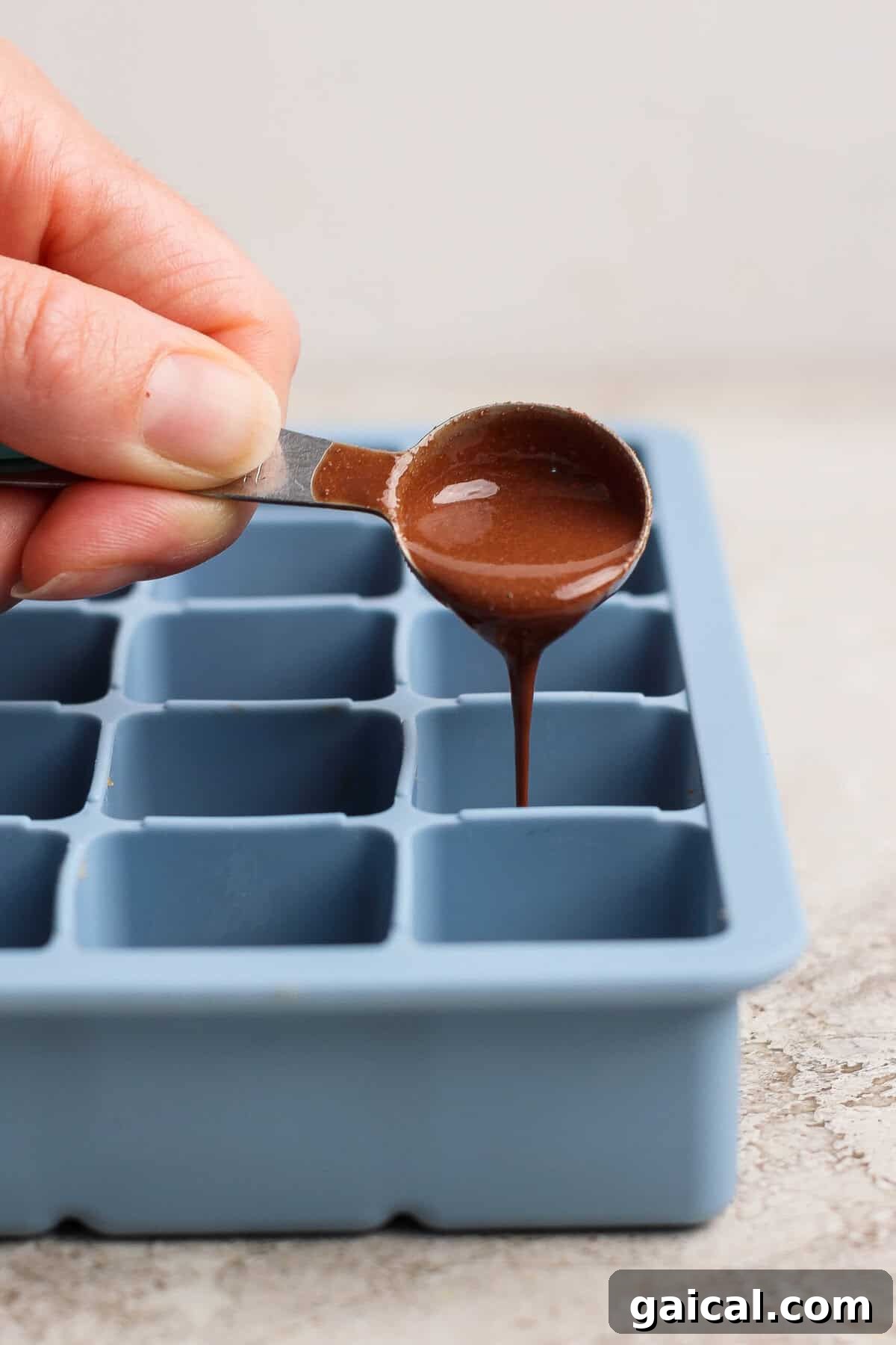 No-Bake Thin Mint Protein Bites 6 pouring melted peppermint chocolate over protein bite base in a silicone tray