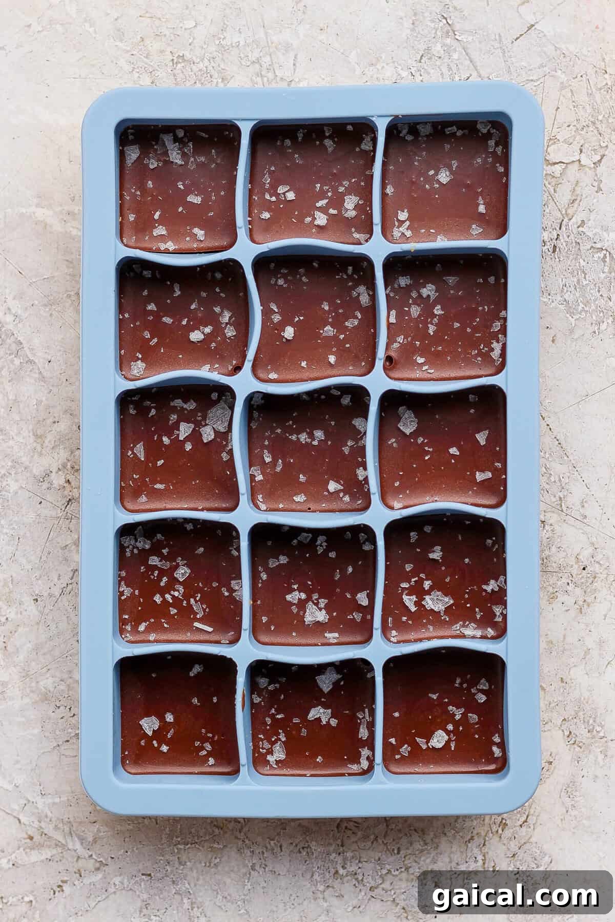 No-Bake Thin Mint Protein Bites 8 thin mint protein bites topped with flaky sea salt in a blue silicone tray before freezing