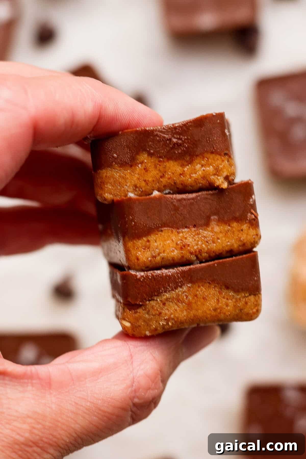 No-Bake Thin Mint Protein Bites 9 hand holding a stack of three no bake thin mint protein bites with chocolate coating