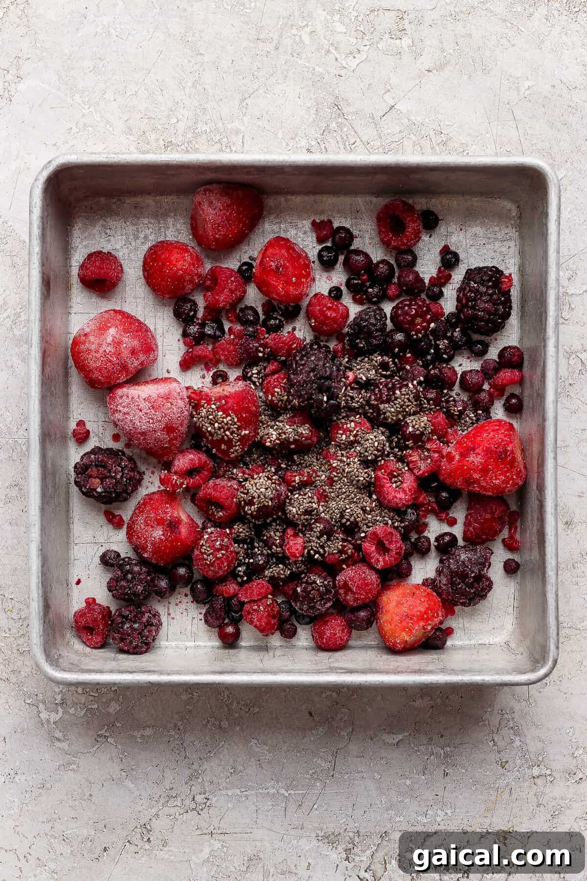 frozen mixed berries tossed with chia seeds spread in a baking pan for protein berry crumble