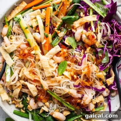 A bowl of asian noodle salad with shrimp and vegetables.