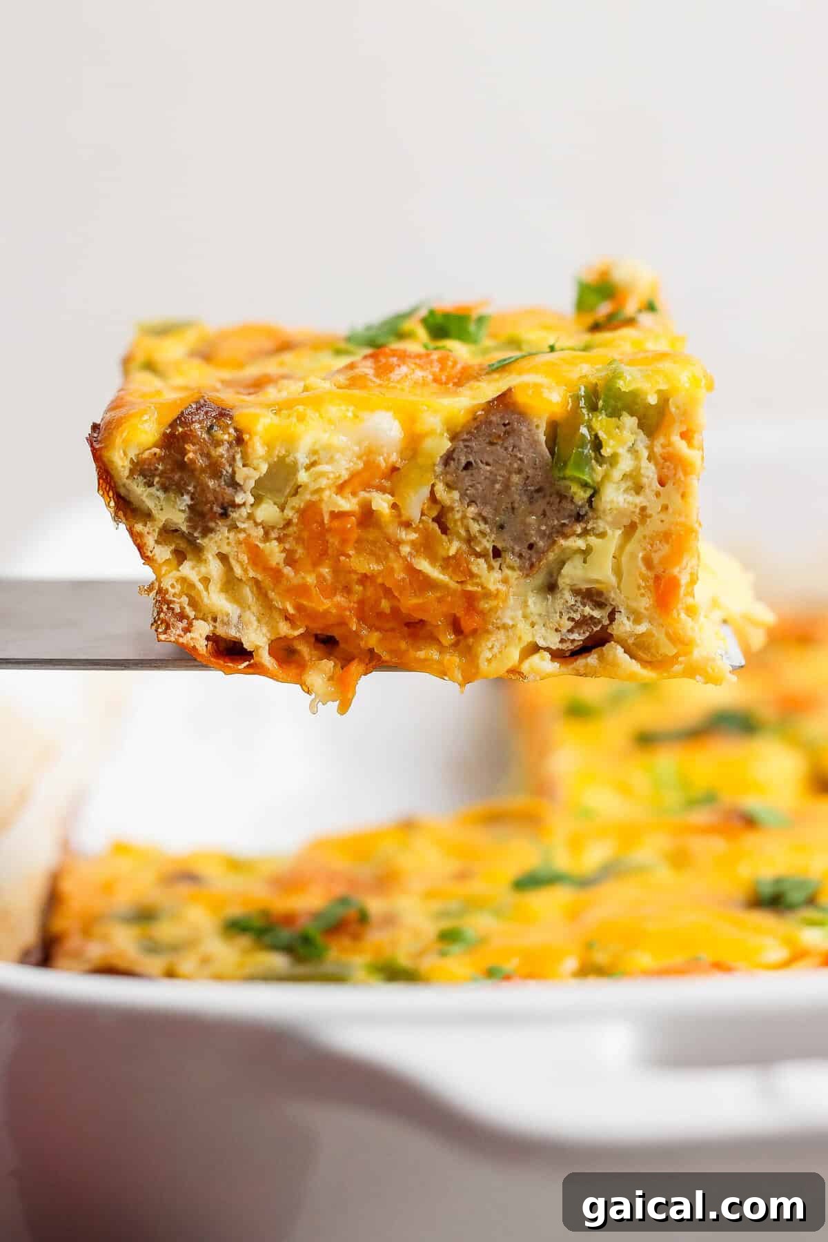 close-up of sweet potato breakfast casserole slice showing tater tots and sausage inside