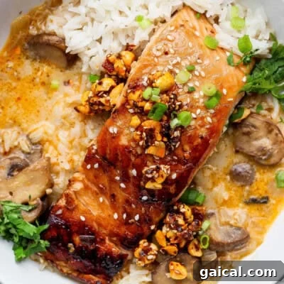 Grilled salmon topped with chopped nuts and green onions, served with white rice, mushrooms, fresh herbs, and a creamy sauce.