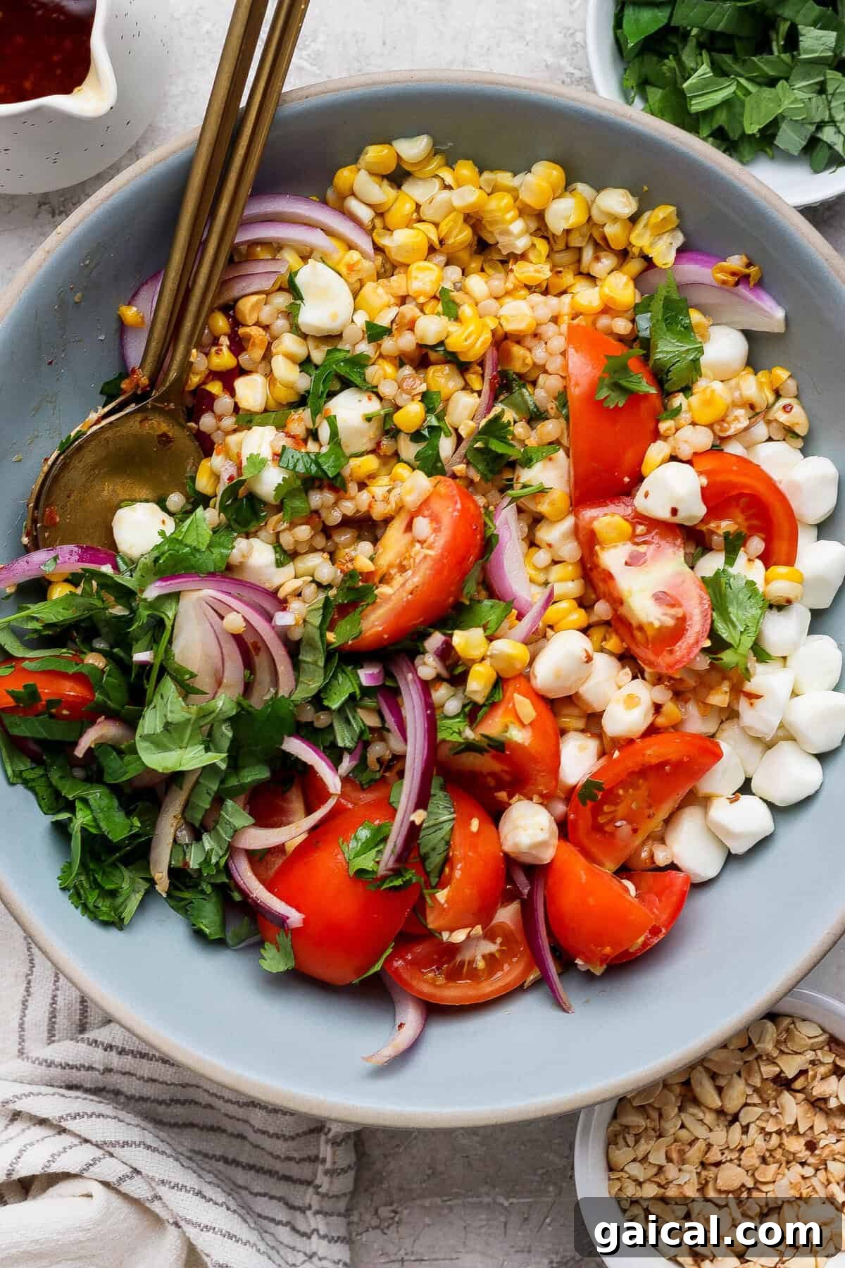 corn tomato salad served in a blue bowl with gold utensils